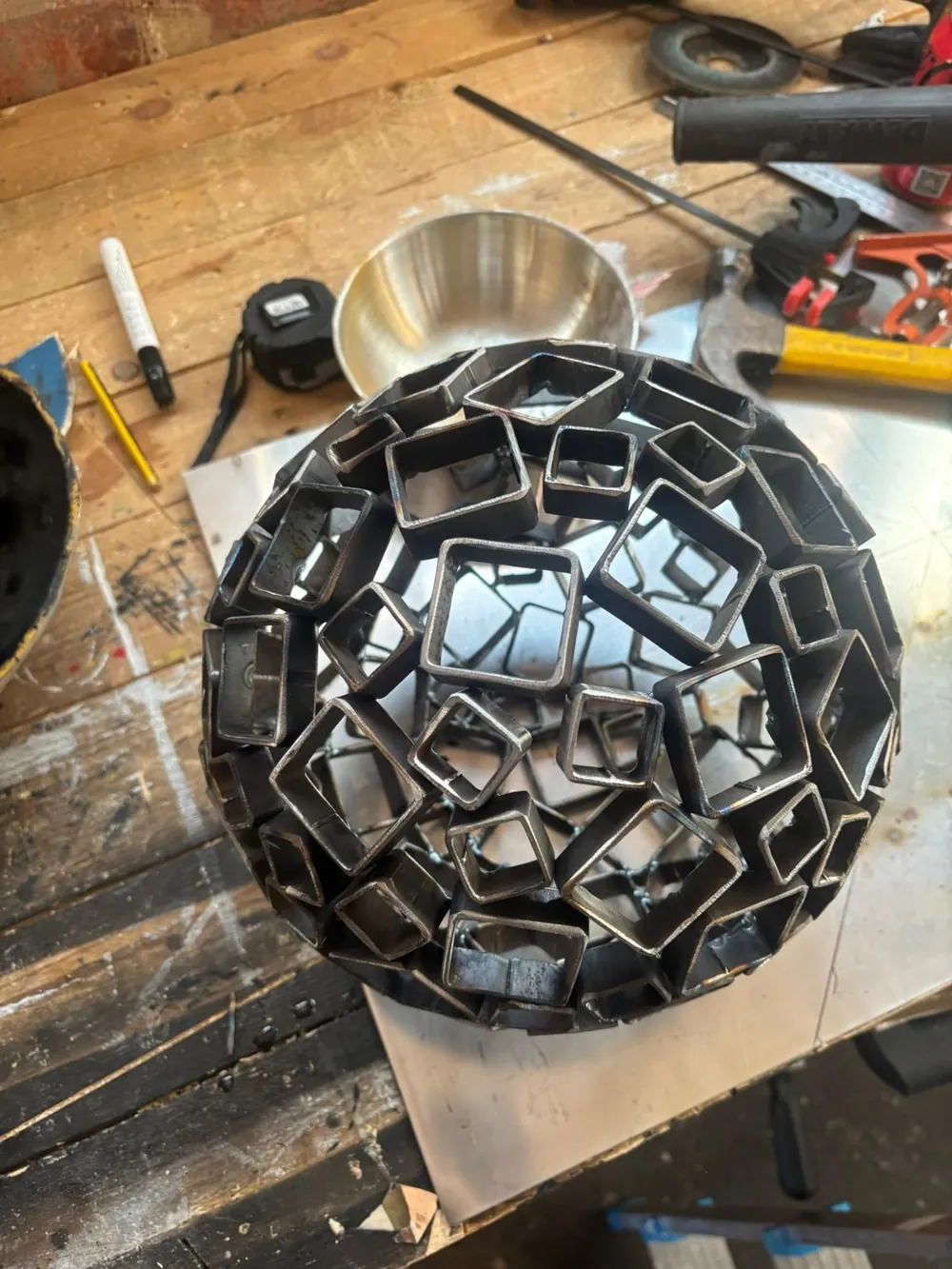 The welded sphere on the workshop bench, tools alongside.